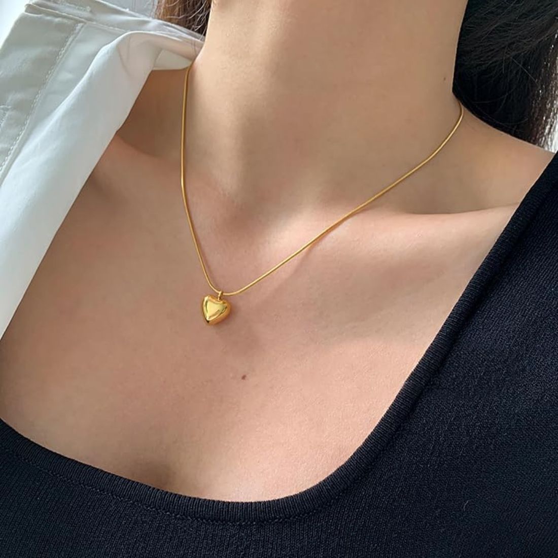 Gold heart-shaped necklace on a Shimmera branded box with wooden surface underneath