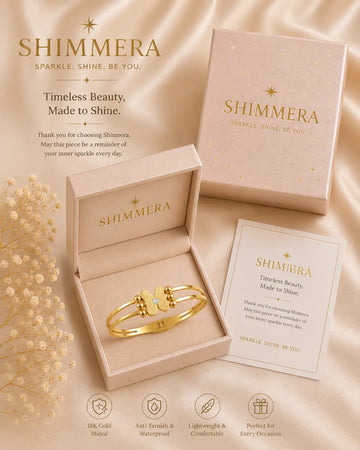 Gold bracelet in a 'Shimmera' box with packaging and card on a satin background