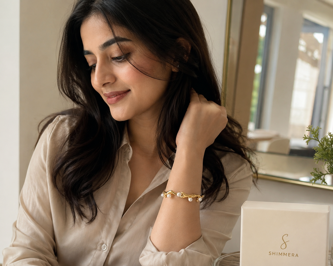 Woman wearing a gold bracelet sitting indoors with a laptop.