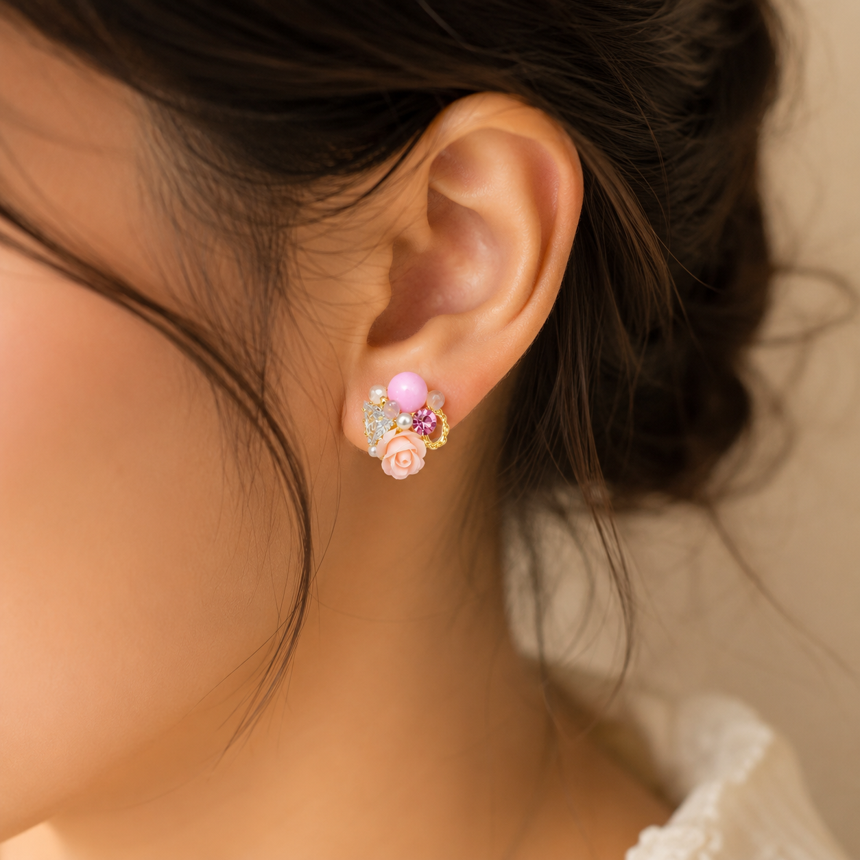 Close-up of an ear wearing a floral earring with pink gemstones.