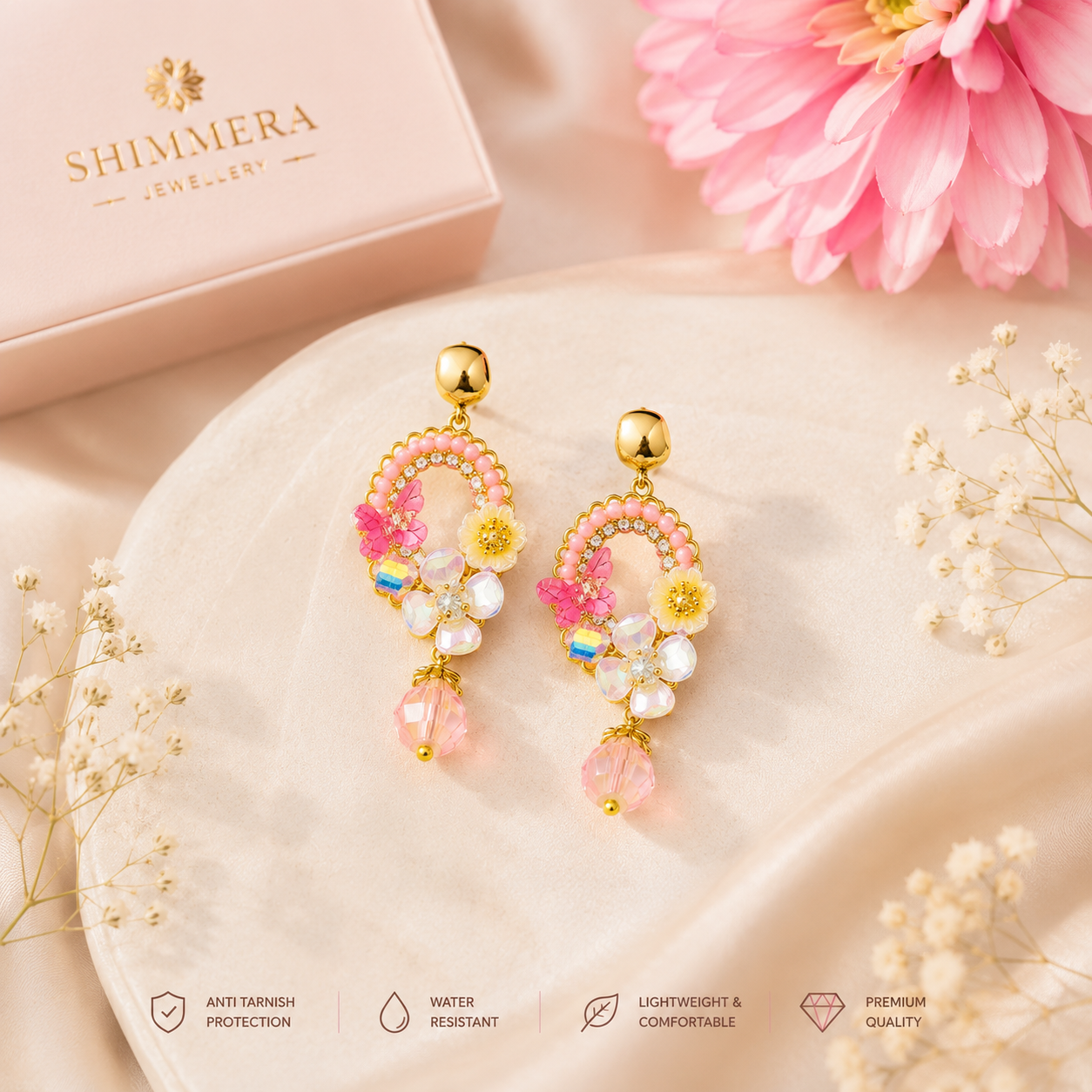 Shimmera jewelry earrings with pink and gold design on a soft surface with flowers.
