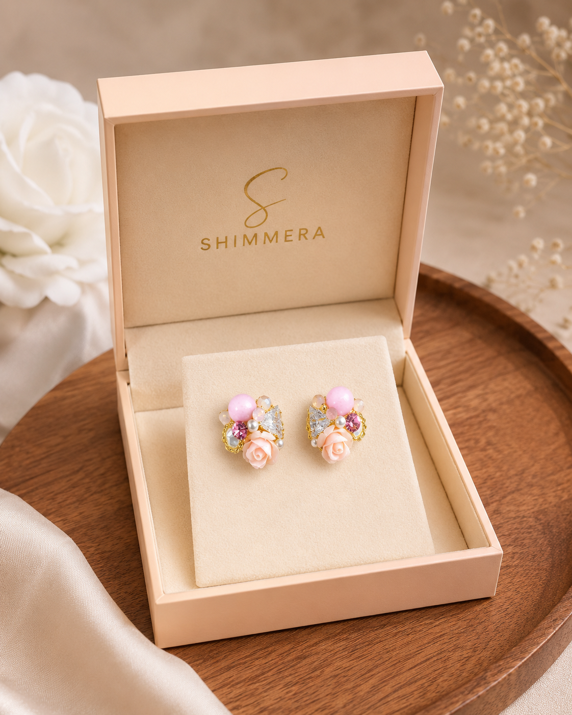 Shimmera earrings in a box on a wooden surface with flowers in the background